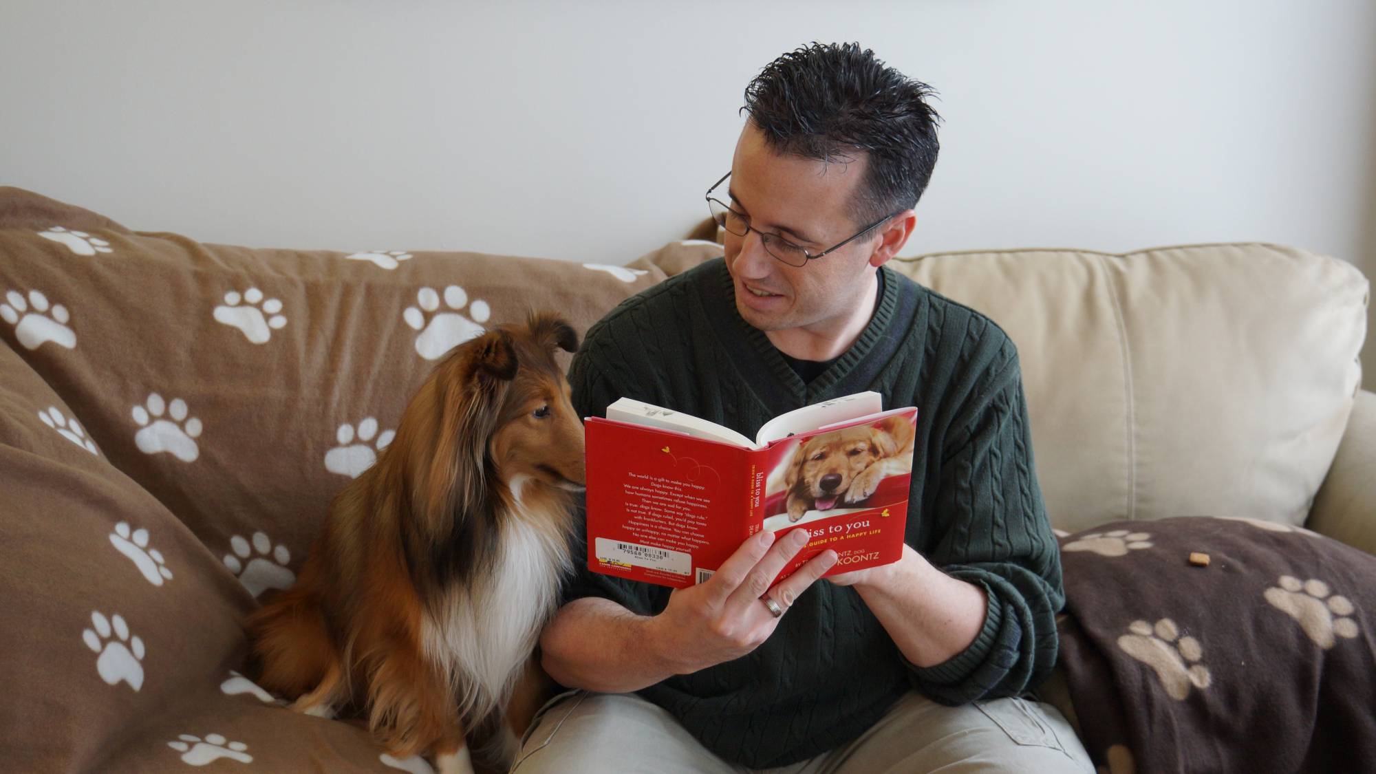 dog and owner sitting on the couch, reading a book
