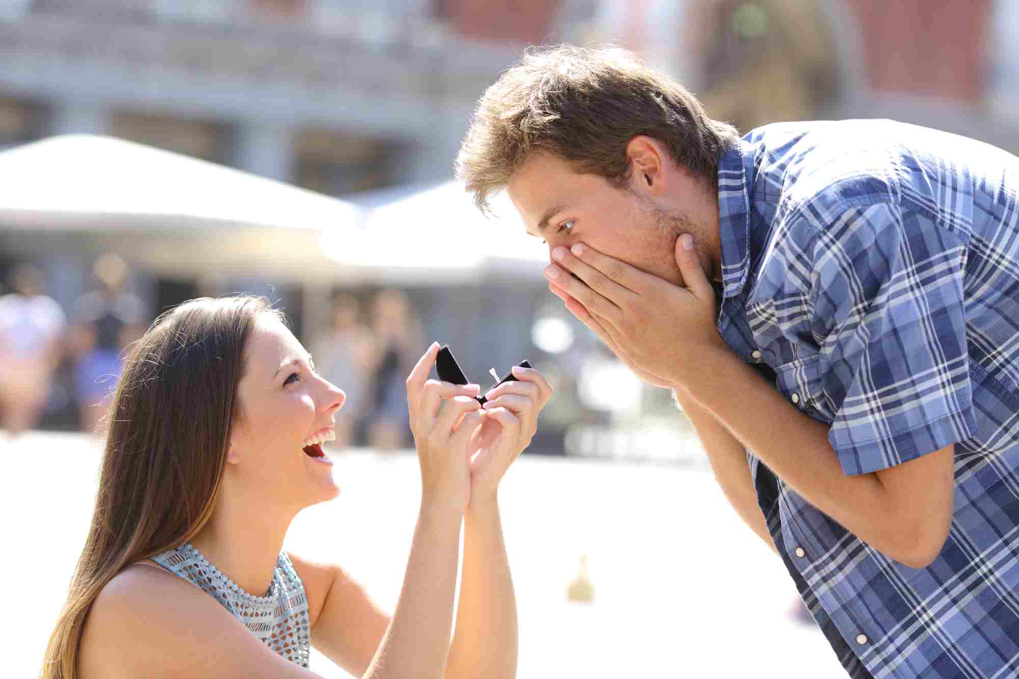 a woman on one knee proposing to a man