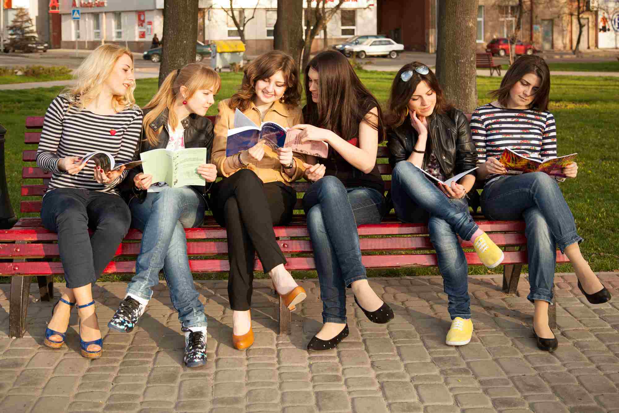 Group of women sitting on a bench, smiling and reading books