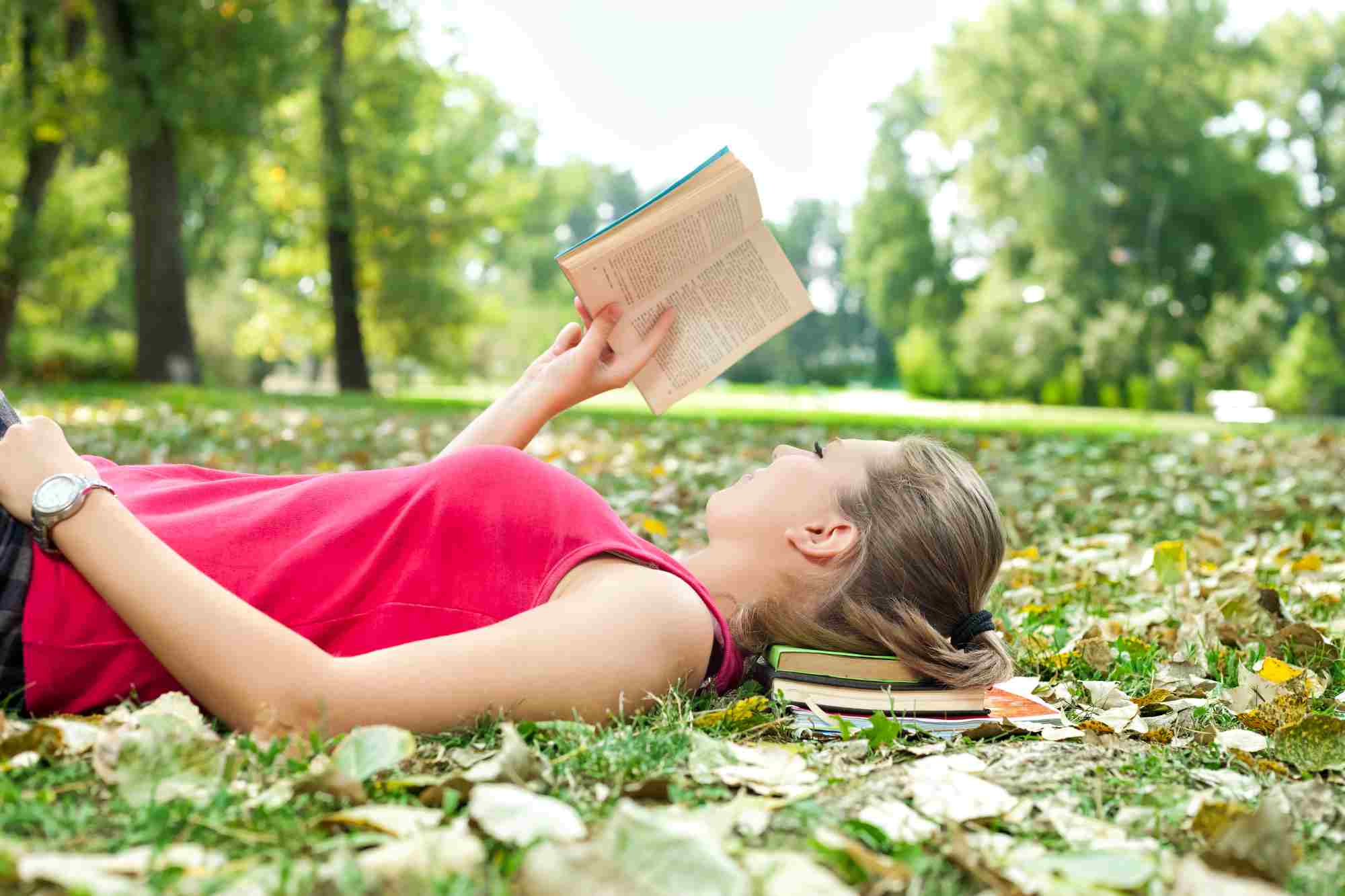 Teenage girl reading while lying in the park