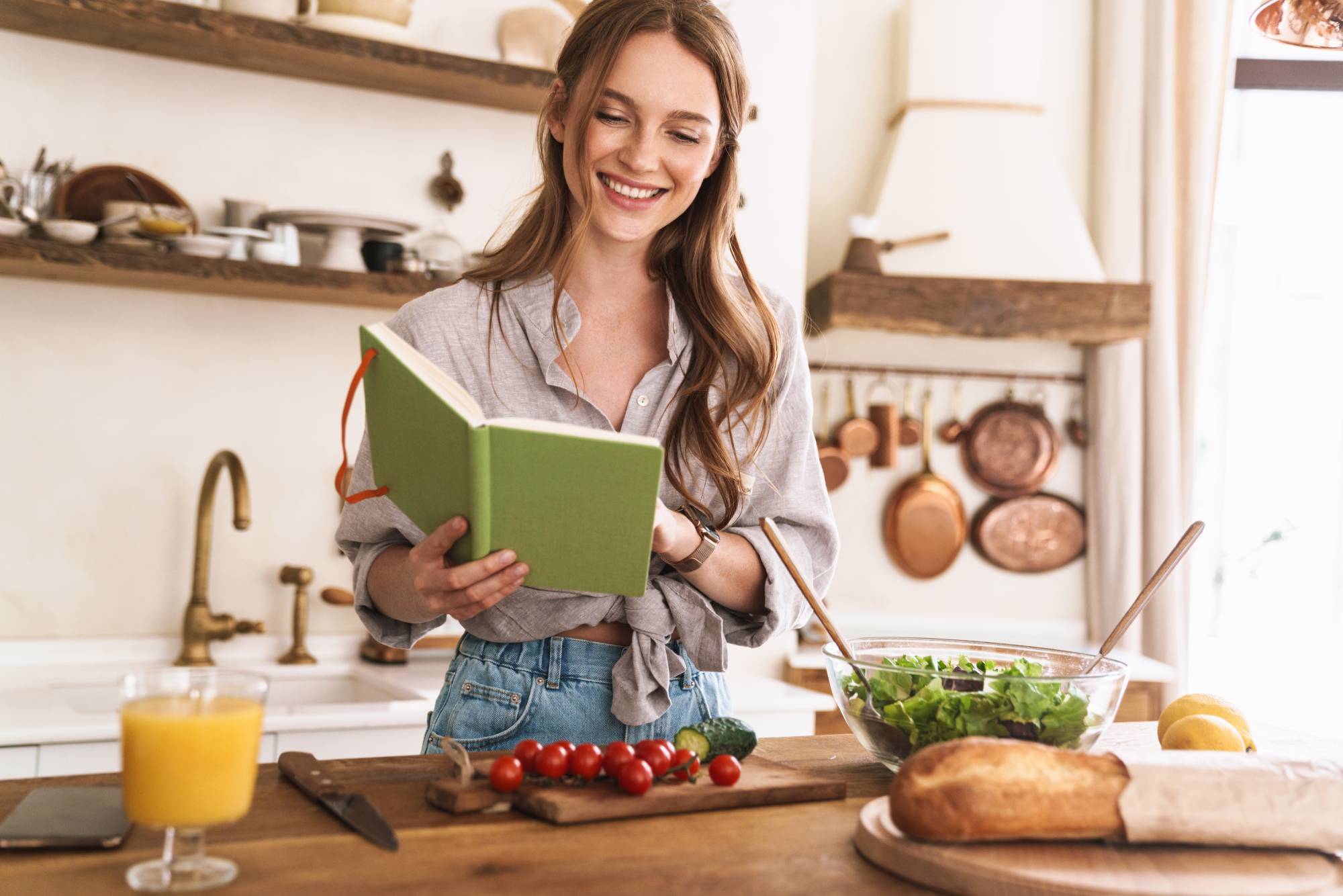 vegan woman in her kitchen laughing and reading a book