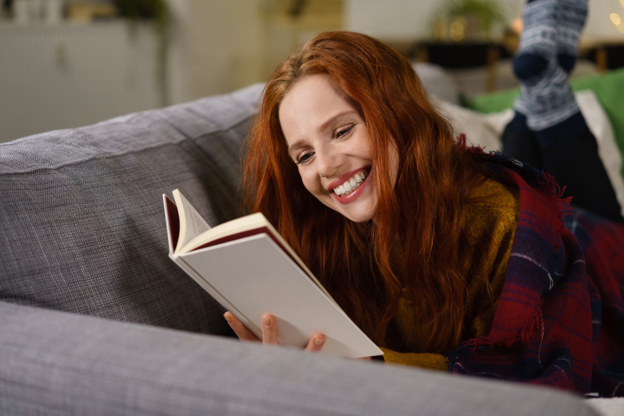 redheaded woman laughing while reading a book