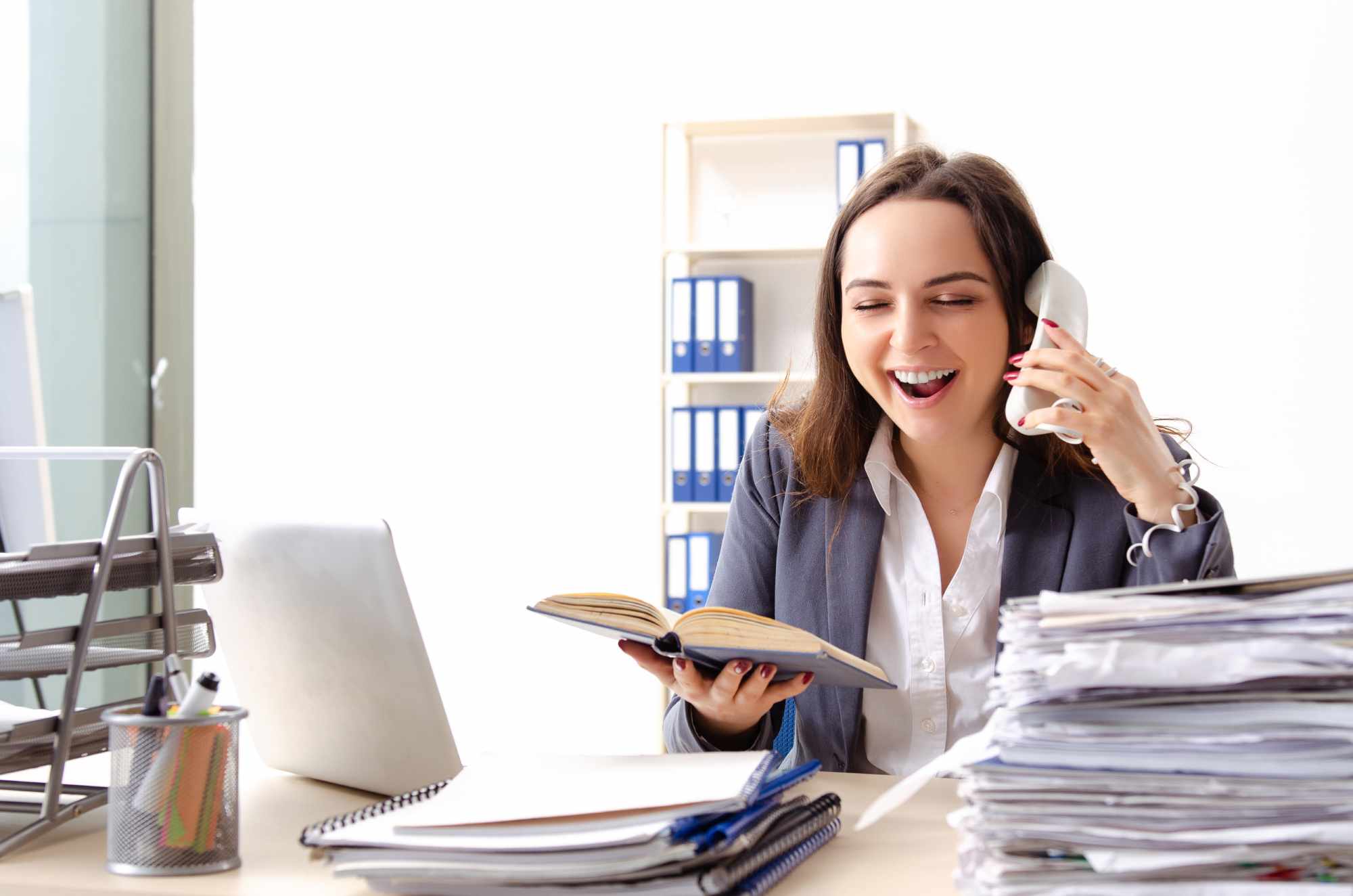 Young female employee unhappy with excessive work but laughing while reading a book