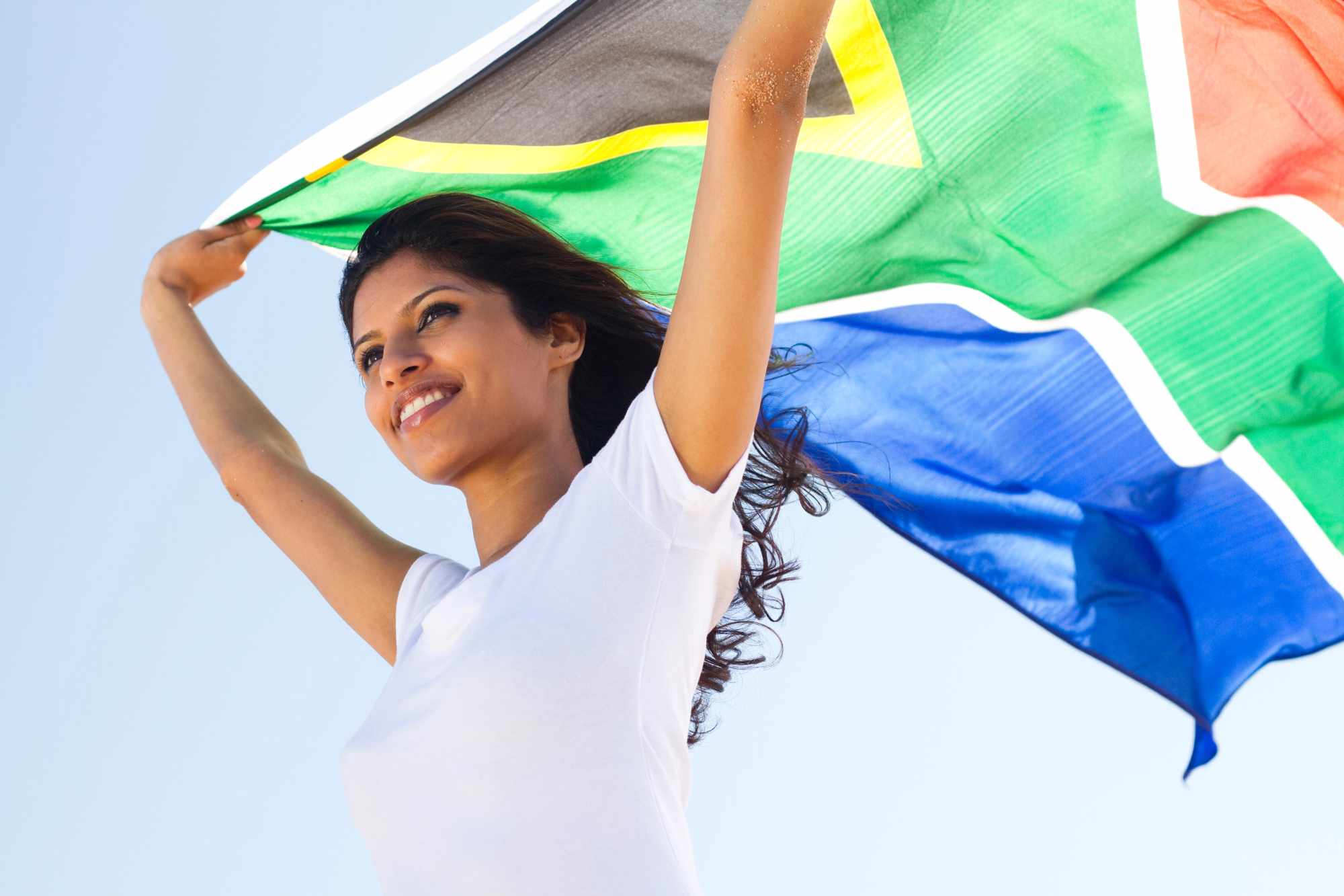 Woman smiling and holding up a south african flag